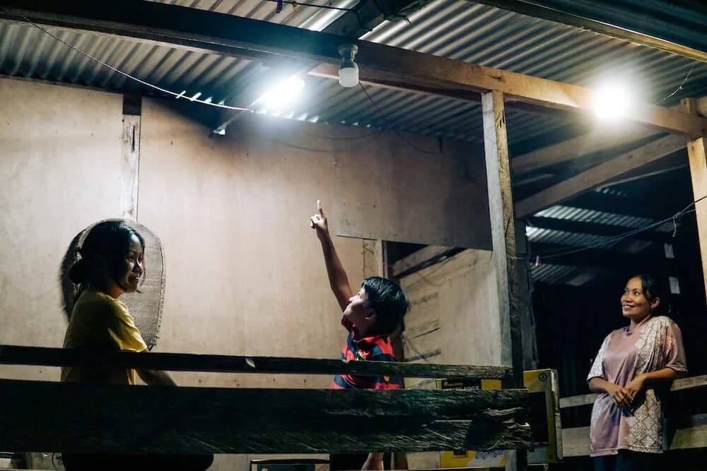 People under a roof light in an open-sided shelter at night